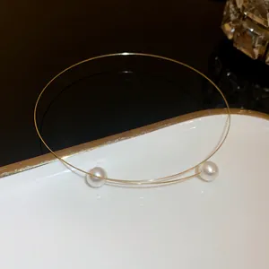 Close-up of minimalist gold wire choker featuring two elegant white pearls.
