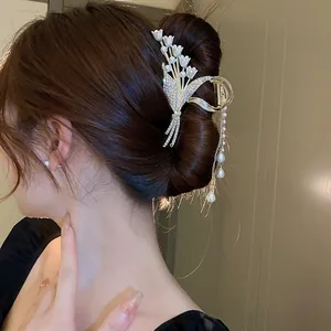 Close-up of elegant lily of the valley hair claw clip with pearl tassels on a bun