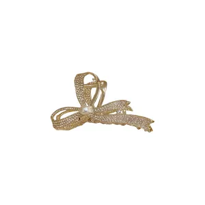 Elegant gold bow hair claw clip featuring sparkling rhinestones and a central pearl accent