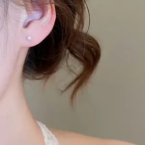 Macro detail view of a minimalist round white pearl stud earring worn on an earlobe