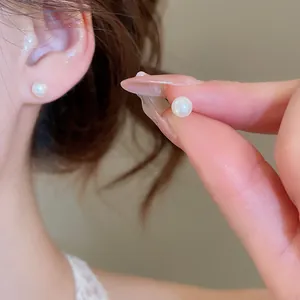Detail view of minimalist round pearl stud earrings with French vintage style on ear