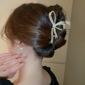 Close-up of elegant silver bow hair claw clip with sparkling rhinestones and pearl