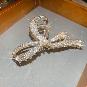 Macro view of a luxurious gold bow hair claw clip with sparkling rhinestones and pearl