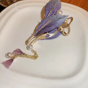 Detail shot of purple leaf hair clip with pearls and rhinestones on a white plate