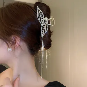 Detailed view of elegant gold leaf hair claw clip with rhinestones and long dangling tassels