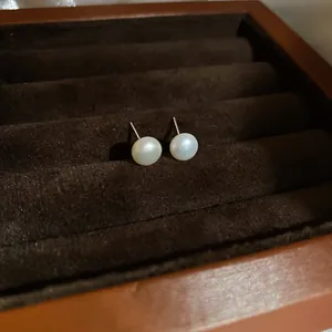 Classic round pearl stud earrings displayed in a luxurious velvet jewelry tray.