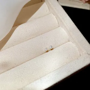 Macro view of elegant minimalist small pearl stud earrings presented in a jewelry tray