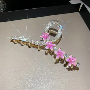 Close-up of luxurious gold-plated shark hair clip with pink flowers and sparkling rhinestones.