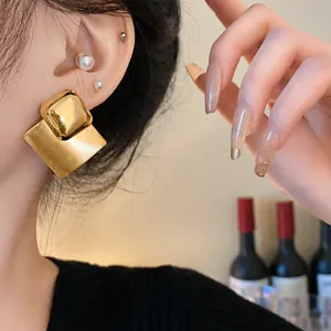 Close-up of gold-plated brushed geometric square earrings on a model's ear