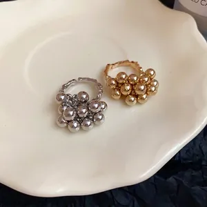 Anelli aperti con perline dorate e argentate su un piatto minimalista di ceramica crema.
