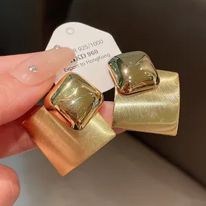 Close-up macro view of gold-plated brushed and polished geometric rhombus stud earrings