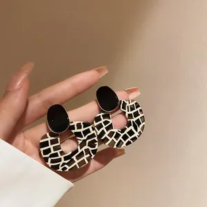 Close-up of stylish acrylic geometric earrings with black and white grid pattern