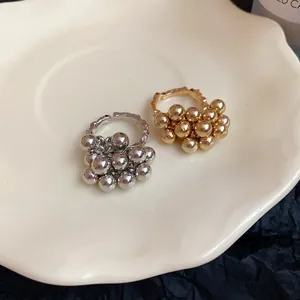 Dettaglio di due anelli aperti irregolari con grappoli di sfere in finitura oro e argento.