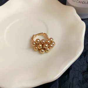 Dettaglio ravvicinato di un anello a grappolo d'oro unico con sfere lucide e fascia testurizzata.