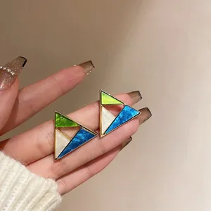 Close-up of geometric triangle earrings with colorful acrylic inlays and gold frame