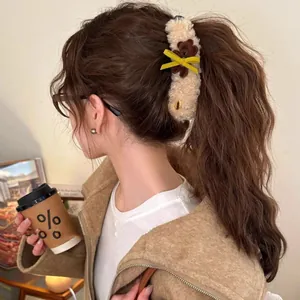 Pinza de felpa con oso pardo y lazo amarillo sobre cabello largo ondulado castaño