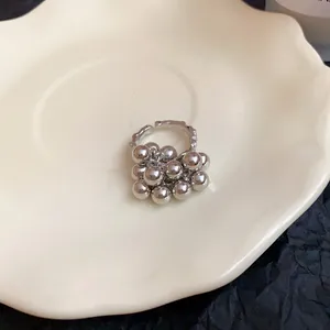 Dettaglio di un anello aperto geometrico argento con un design a grappolo di sfere metalliche