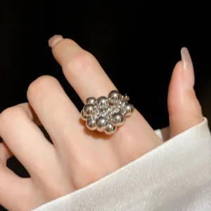 Dettaglio di un anello unico a grappolo di perle d'argento indossato sul dito