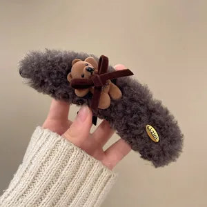 Detalle de una suave pinza de pelo de peluche gris con un lindo osito de peluche marrón