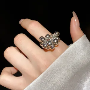 Primo piano dettagliato di un anello aperto a grappolo di sfere geometriche argentate sul dito