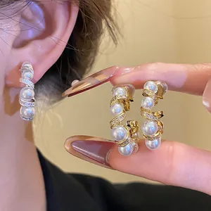 Détail de boucles d'oreilles clips C torsadées plaquées or 18 carats avec perles
