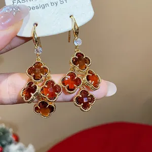Macro view of detailed 18k gold plated drop earrings with amber zircon four-leaf clover charms