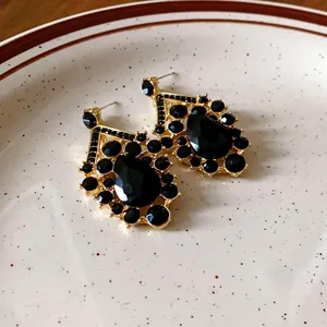 Nahaufnahme von goldenen Vintage-Ohrringen mit eleganten schwarzen Kristallfassungen.