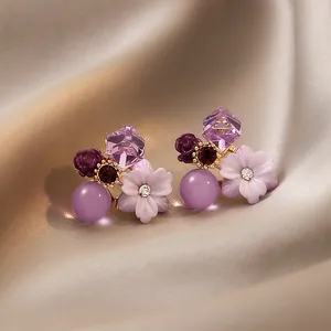 Detail view of purple floral crystal earrings with silver needles and rhinestones.