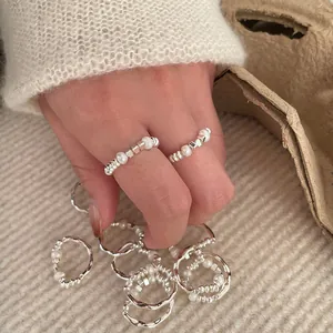 Minimalist elastic ring featuring irregular pearls and silver beads shown on hand.