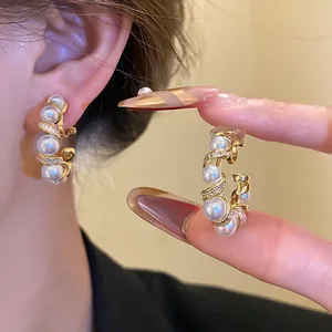 Détail de boucles d'oreilles clips élégantes en forme de C dorées avec perles et zircons vintage