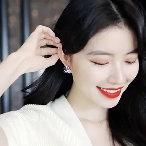 Close-up of elegant purple crystal flower earrings on a smiling female model