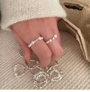 Macro detail view of minimalist silver elastic rings with white pearls worn on a hand