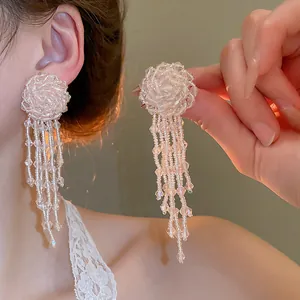 Close-up of elegant pink crystal beaded flower tassel earrings worn on a model's ear