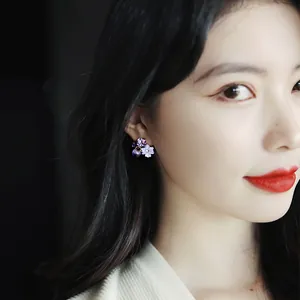 Close-up of elegant purple and white flower earrings with crystals on an Asian model