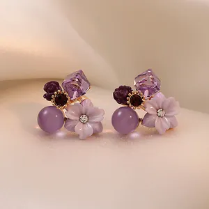 Macro view showing the intricate purple crystal and resin flower details on stud earrings