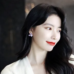 Detailed close-up of elegant purple flower crystal stud earrings worn by an Asian model