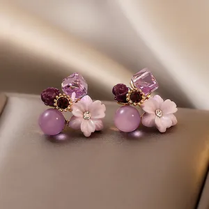 Close-up of elegant purple flower stud earrings with crystal and cat-eye stone details