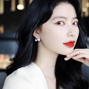 Detailed view of elegant purple crystal flower stud earrings worn by an Asian model