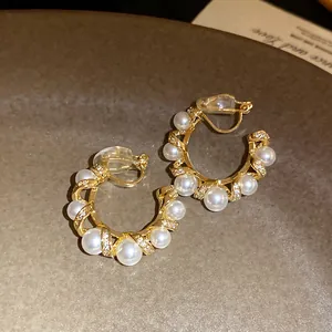 Détail de boucles d'oreilles clips en C plaquées or 18 carats avec perles et zircons