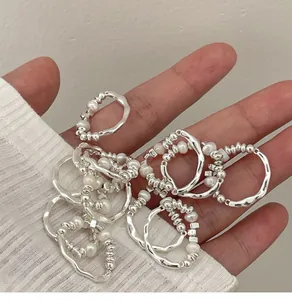 Close-up of minimalist silver elastic rings with pearls held in hand