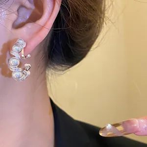 Gros plan d'une boucle d'oreille torsadée en C avec des perles blanches et des zircons