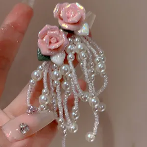 Close-up of pink flower earrings with pearl bead tassels and crystal accents