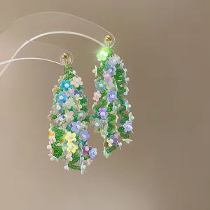 Close-up detail of colorful floral beaded tassel earrings on a transparent earring stand