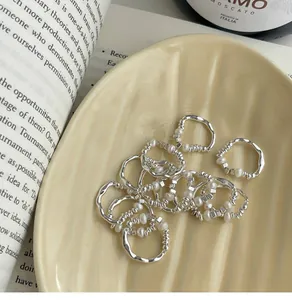 Detailed view of silver irregular pearl elastic rings on a cream ceramic dish
