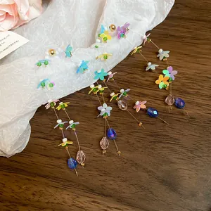 Close-up of colorful flower tassel earrings with crystals and iridescent sequins.