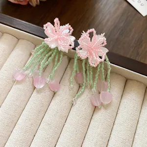 Close-up detail of forest style flower earrings with green seed bead tassels and charms