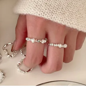 Close-up of minimalist elastic rings featuring irregular pearls and silver-toned beads.