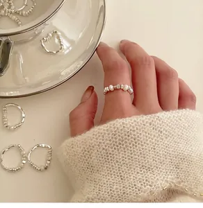 Close-up of minimalist irregular pearl elastic ring worn on hand with cozy knit