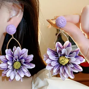 Detail view of purple fabric raffia flower earrings showing texture and wearing effect