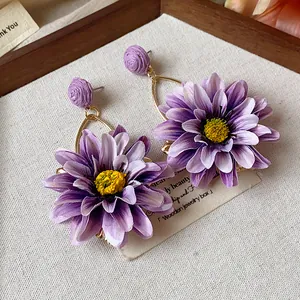 Detailed macro view of purple fabric flower earrings with yellow centers for vacation